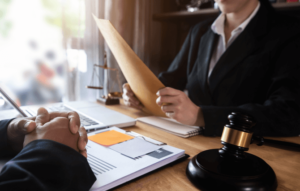 A nursing home abuse lawyer holds a manila folder while sitting with a client at a desk.