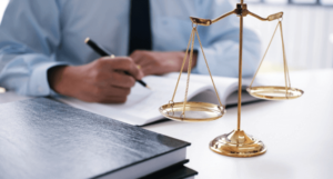 A nursing home abuse lawyer writes at a desk with the scales of justice and books.